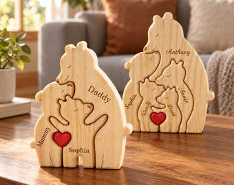 Può includere: Due puzzle in legno chiaro a forma di famiglia di orsi con nomi incisi e un piccolo cuore rosso. Il primo puzzle include i nomi Mummy, Daddy e Sophia. Il secondo puzzle riporta i nomi Anthony, Sophia, Wendy, Paul e Annie.