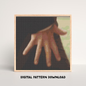 May include: A cross-stitch design of a hand with open fingers, framed in wood. The needlework uses tan, brown, and black threads. The text "DIGITAL PATTERN DOWNLOAD" is displayed at the bottom of the frame.