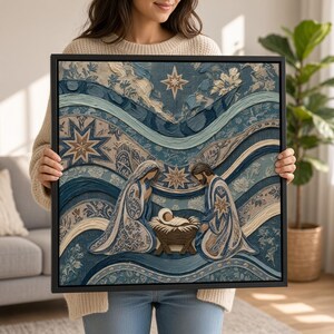 May include: A square framed wall art piece featuring a textured nativity scene in shades of blue, cream, and brown. The artwork depicts two figures kneeling beside a central manger with a baby, set against wavy patterns and star motifs.