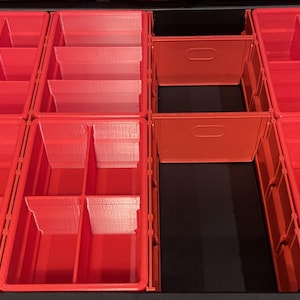 May include: A set of red plastic storage bins with various internal dividers arranged in a grid pattern inside a black container. The bins feature multiple compartments of different sizes, including square and rectangular sections for organising small items.
