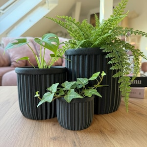 Può includere: Una tazza di ceramica bianca con manico nero e la scritta "But First, Coffee" in nero, con un carattere a mano. La tazza è su una superficie bianca.