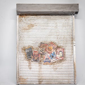 Könnte beinhalten: Ein dekoratives Wandelement aus weiß lackiertem Holz mit grauem Oberteil. Mehrere farbenfrohe Zeitschriften-Cover im Vintage-Stil sind auf der Vorderseite angebracht. Die Zeitschriften zeigen Bilder von Kaffee, Burgern und Musik.