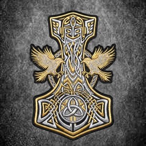 Könnte beinhalten: Ein bestickter Aufnäher mit einem zentralen Mjolnir-Hammer-Design aus Gold- und Silberfaden. Zwei symmetrische goldene Raben flankieren den oberen Schaft, während ein silberner Triquetra-Knoten in der Basis des Hammerkopfes zentriert ist.
