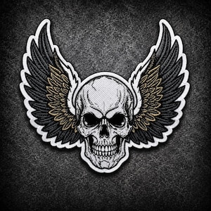 May include: An embroidered patch featuring a central human skull in white and grey tones, flanked by two large, detailed wings. The wings are primarily black with white outlines and subtle gold-toned accents within the feather detailing.