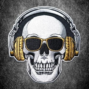 Pode incluir: Um emblema bordado apresentando um crânio humano branco usando óculos de sol pretos com armação dourada e grandes fones de ouvido dourados. O design usa fios pretos, brancos e dourados para criar um gráfico detalhado de um crânio ouvindo música.