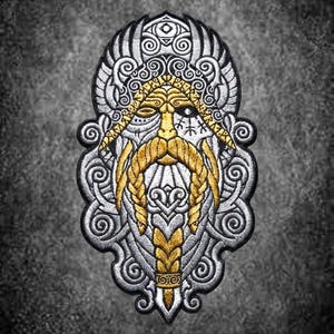 Może przedstawiać: Haftowana naszywka przedstawiająca stylizowaną twarz z długą, plecioną złotą brodą i wąsami, otoczoną misternymi srebrnymi zawijasami i skrzydłami. Wzór zawiera złotą opaskę z symbolami runicznymi oraz jedno widoczne oko.