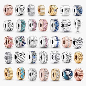 Könnte beinhalten: Eine Sammlung von fünfunddreißig verschiedenen Metallanhängern für Armbänder mit diversen Designs wie Herzen, Blumen, Sternen, geometrischen Mustern und Edelsteinakzenten in Silber-, Gold-, Roségold- und Blautönen mit klaren Kristallen.