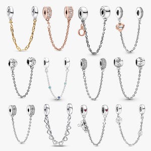 May include: A collection of silver charm bracelet safety chains. The chains feature various designs, including a gold chain, chains with clear and rose-colored stones, and charms with hearts, flowers, and Mickey Mouse.