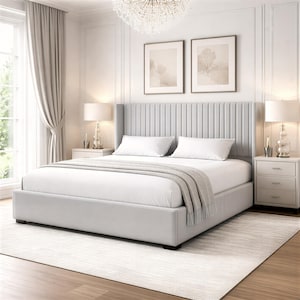 May include: A contemporary bedroom scene with a light grey upholstered bed. The bed has a tall, vertically-lined headboard and is dressed with white bedding and a grey throw. Matching bedside tables with lamps are on either side. The room has a neutral colour scheme.