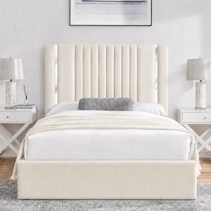 May include: A cream-coloured upholstered bed with a vertically panelled headboard. The bed frame and headboard are the same colour. Two white bedside tables with lamps flank the bed. A grey bolster pillow and a white blanket are on the bed.