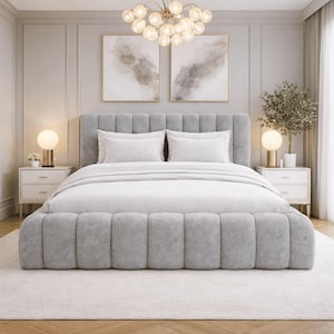 May include: A contemporary bedroom scene with a grey upholstered bed, featuring a tufted headboard and footboard. The bed is dressed with white bedding and pillows. Two white bedside tables with gold accents are positioned either side of the bed. A chandelier hangs above.