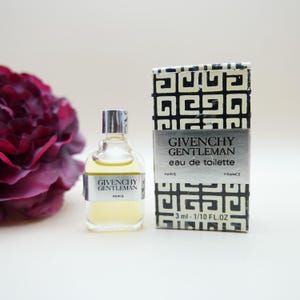 May include: A miniature glass bottle of Givenchy Gentleman eau de toilette with a silver label and a matching rectangular box featuring a black and white geometric pattern. The box displays the text Givenchy Gentleman eau de toilette 3 ml - 1/10 FL.OZ.