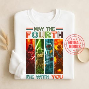 Könnte beinhalten: Weißes Sweatshirt mit einem farbenfrohen Aufdruck von Darth Vader, Yoda, Boba Fett und Chewbacca. Der Text lautet "MAY THE FOURTH BE WITH YOU". Ein Bonus-Aufkleber ist sichtbar.
