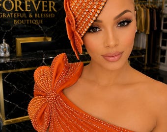Oranje fascinator in de vorm van een bloem met strasssteentjes in druppelvorm.