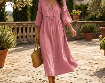 May include: A dusty rose midi dress made of polyester fabric featuring a V-neckline, three-quarter length sleeves, and decorative cut-out detailing along the neckline and waist. The dress has a loose, flowing skirt and is paired with a woven straw tote bag.
