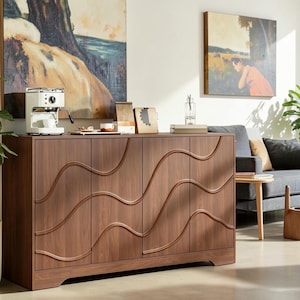 May include: A rectangular wooden sideboard featuring four cabinet doors with a continuous, raised wavy line pattern across the front. The piece has a dark brown wood grain finish and is supported by a solid base with a slight cutout at the bottom.