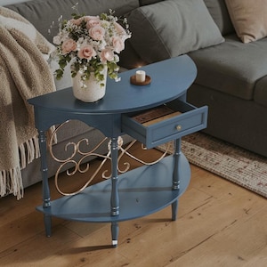 May include: A blue half-moon console table with a drawer, gold accents, and a lower shelf. A vase of pink roses and a candle sit on top. The table is approximately 30 inches wide and 15 inches deep.