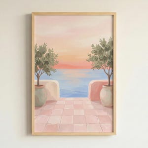 May include: A framed painting shows a coastal scene with a pink and orange sunset over the sea. Two potted olive trees flank a tiled patio overlooking the water. The artwork is in a light wood frame.