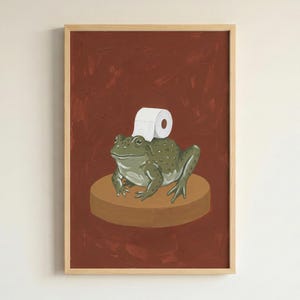 Divertida lámina decorativa de pared con forma de rana y rollo de papel higiénico para el baño.