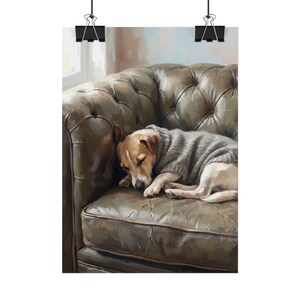 May include: A small dog with brown and white fur wearing a grey knitted sweater, curled up and sleeping on a dark olive green tufted leather sofa. The artwork is displayed as a vertical poster held by two black metal clips at the top edge.