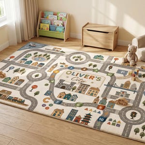 May include: A rectangular area rug featuring a printed city map design with roads, buildings, trees, and water elements. The center displays the text 'OLIVER'S City' surrounded by a castle, houses, numbered blocks, and a train track illustration.