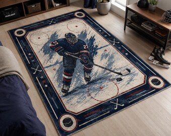Puede incluir: Alfombra rectangular con temática de hockey con un borde azul y una imagen central de un jugador de hockey en acción. La alfombra presenta un diseño de pista de hockey con una combinación de colores azul y blanco, discos y palos.