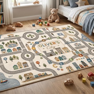 May include: A rectangular area rug featuring a printed city map with roads, buildings, trees, a train, and a boat. The center of the rug displays the text "OLIVER'S City" surrounded by numbered and lettered paths in shades of blue, green, and tan.
