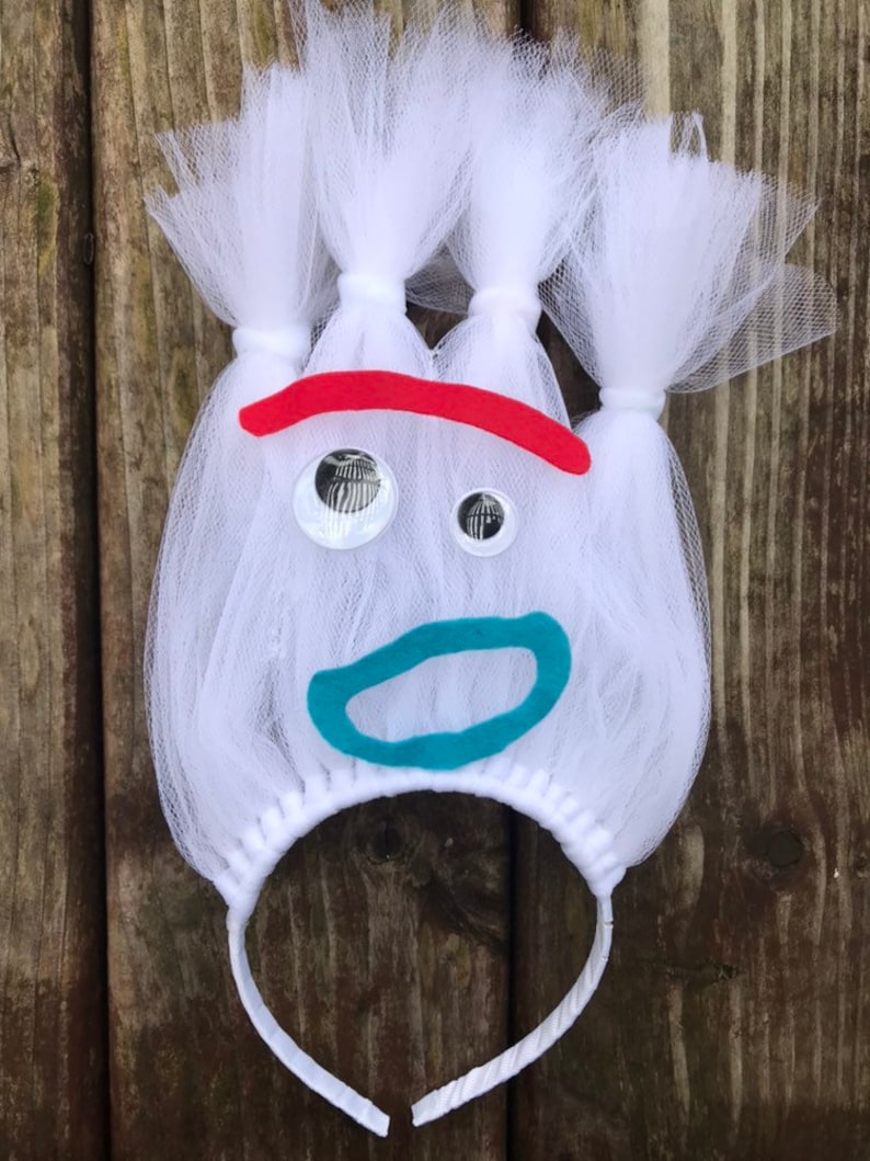 May include: White tulle headband with a red, blue, and white felt face. The face has two large white eyes, a red eyebrow, and a blue mouth.