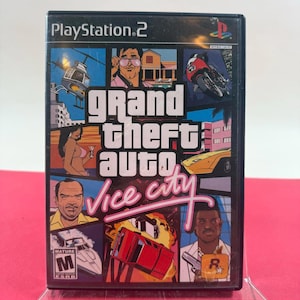 Puede incluir: Caja de videojuego de PlayStation 2 para Grand Theft Auto: Vice City. La portada presenta un collage de imágenes que incluyen un helicóptero, una motocicleta y varios personajes. El título del juego se muestra de forma destacada en letras blancas y rojas.