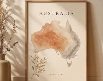 May include: A framed wall art print featuring a topographic map of Australia in shades of orange, beige, and grey. The text reads AUSTRALIA and 7,692,024 km². A small illustration of a yellow flowering branch is at the bottom left corner.