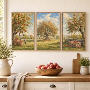 May include: A triptych wall art set featuring three framed landscape paintings of apple orchards. The left panel shows a ladder against an apple tree, the center shows a large tree in a field, and the right shows a wooden crate filled with red apples.