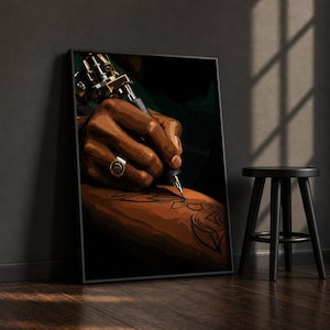 Könnte beinhalten: Ein gerahmter Wandkunstdruck, der eine dunkelhäutige Hand zeigt, die eine metallische Tätowiermaschine hält und ein florales Design mit schwarzer Tinte auf die Haut zeichnet. Die Hand trägt einen goldenen Ring mit einem kreisförmigen Emblem.