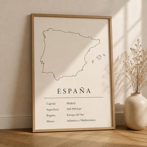 May include: A framed wall art print featuring a black line map of Spain on a cream background. The text reads ESPAÑA, Capital: Madrid, Superficie: 505.990 km², Región: Europa del Sur, Mares: Atlántico y Mediterráneo. The frame is light wood.