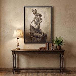 Könnte beinhalten: Sepiafarbene, gerahmte Kunstwerk, das einen Hasen mit Tweedmütze, Weste und Hose zeigt, der eine Zigarette raucht. Das Kunstwerk wird über einer Holzkonsolentisch mit Lampe, Büchern und einer Topffarnpflanze ausgestellt.