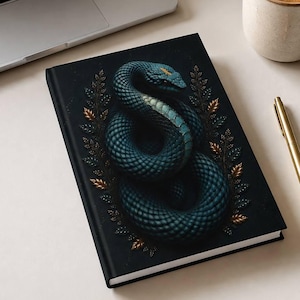 Peut inclure: Un carnet rectangulaire à couverture noire orné d'une illustration de serpent bleu foncé enroulé, entouré de petites feuilles dorées et bleues. Le carnet est posé sur une surface à côté d'un ordinateur portable argenté, d'un stylo doré et d'une tasse de café.