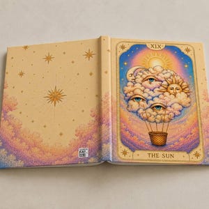 Può includere: Un libro con copertina rigida color marrone chiaro caratterizzato da un motivo a stelle dorate e un'illustrazione centrale di una mongolfiera fatta di nuvole con occhi, un sole e una luna. La copertina riporta il testo XIX e THE SUN in oro.