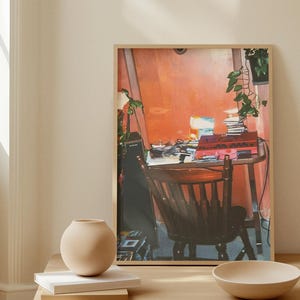 Peut inclure: Une œuvre d'art encadrée représente un intérieur de pièce avec une chaise en bois, une table et un mur rouge. Un vase beige, des livres et un bol sont posés sur une table en bois au premier plan. L'œuvre a une palette de couleurs chaleureuse.