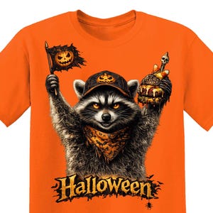 May include: A bright orange t-shirt featuring a graphic of a raccoon wearing a pumpkin-patterned cap and bandana. The raccoon holds a tattered flag with a jack-o'-lantern and a burger topped with a skull. The word Halloween is printed below.