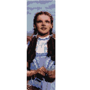 May include: A beaded bracelet featuring a portrait of Dorothy from The Wizard of Oz. The bracelet depicts a blue and white dress, brown hair, and a brown jacket.