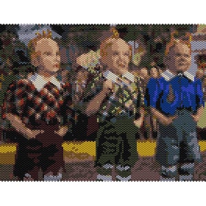 May include: Three children wearing matching outfits stand in a row. The child on the left is wearing a red and black plaid dress, the middle child is wearing a green and black plaid shirt, and the child on the right is wearing a blue shirt. All three children have blonde hair and are smiling.