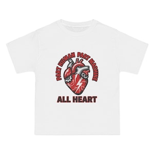 May include: A white short-sleeve t-shirt featuring a graphic of a red anatomical heart integrated with mechanical gears and a lightning bolt. The text "PART HUMAN PART MACHINE" arches above the heart, and "ALL HEART" is printed below in red.