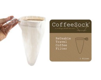 May include: White reusable coffee filter sock with a metal clip. The filter is in a cone shape and is made of a soft, natural fabric. The text on the brown label reads "CoffeeSock® as it always should have been Reusable Travel Coffee Filter 1 Filter".