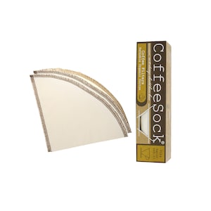 May include: Three white reusable coffee filters made of organic cotton, folded and stacked on a white background. The filters are surrounded by a brown stitched border. A brown box with the text "Coffeesock" and "Reusable organic cotton" is on the right side of the image.