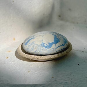 Peut inclure: Un porte-savon en céramique ovale avec un motif bleu et blanc marbré. Le porte-savon repose dans une coupelle peu profonde assortie. Le motif évoque un effet tourbillonnant.