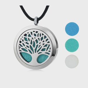 Peut inclure: Pendentif d'aromathérapie argenté avec un motif d'arbre de vie, suspendu à un cordon noir. Le pendentif rond contient un intérieur turquoise et est accompagné de trois tampons absorbants colorés : bleu, turquoise et blanc.