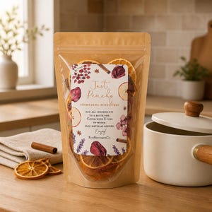 May include: A clear and brown pouch of simmering potpourri containing dried orange slices, cinnamon sticks, and botanicals. The label reads Just Peachy Simmering Potpourri, with instructions to add all ingredients to a saucepan and cover with 2 cups of water.
