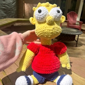May include: A handmade, crocheted doll in the likeness of a cartoon character. The doll has a yellow head, a red shirt, blue shorts, and white and blue shoes. The text "Pattern Only!!" is at the top of the image.