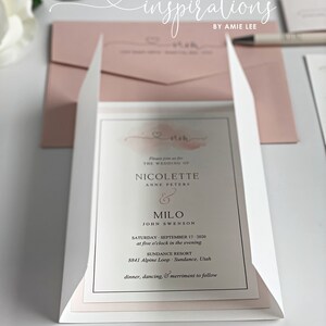 May include: Wedding invitation suite featuring a white and blush pink color scheme. The invitation includes the names Nicolette and Milo, the wedding date, time, and location. The text "inspirations by Amie Lee" is at the top.