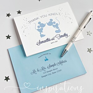 Puede incluir: Juego de papeler&iacute;a de boda. Una tarjeta blanca con siluetas azules de Mickey Mouse y el texto "Thank You Kindly". Los nombres "Samantha and Timothy" est&aacute;n escritos debajo. Una envoltura azul claro est&aacute; debajo, con detalles de la direcci&oacute;n y un bol&iacute;grafo.