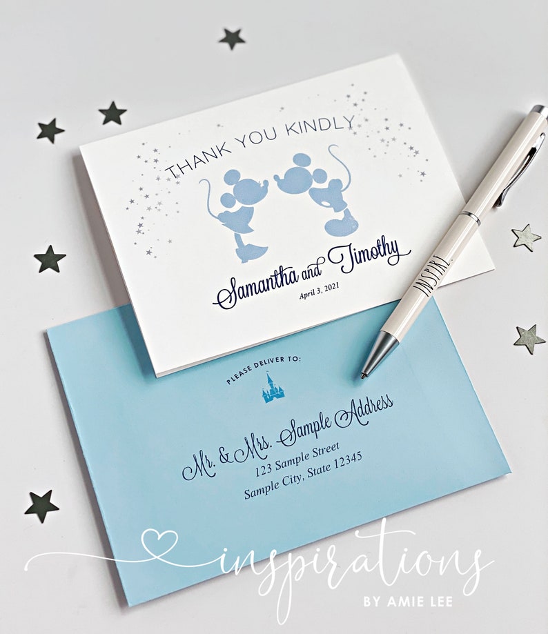 Puede incluir: Juego de papeler&iacute;a de boda. Una tarjeta blanca con siluetas azules de Mickey Mouse y el texto "Thank You Kindly". Los nombres "Samantha and Timothy" est&aacute;n escritos debajo. Una envoltura azul claro est&aacute; debajo, con detalles de la direcci&oacute;n y un bol&iacute;grafo.